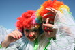Two bizzare clowns in colored wigs upon blue sky Two bizzare clowns in colored wigs upon blue sky
