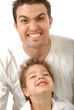 Young father making funny scary faces with his little son