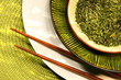 Asian chopsticks, bowls filled with herbs and green mat