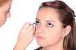 Makeup artist applying eye liner to model's eyes