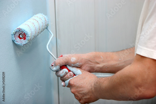 house painter using a paint roller, painting a wall in motion