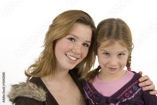 Foto: two cute sisters embracing against white background two cute sisters embracing against white background