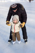 Photo: Winter recreation. Father and child skating on rink Winter recreation. Father and child skating on rink