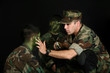 Father puting camo paint on children's faces over black.