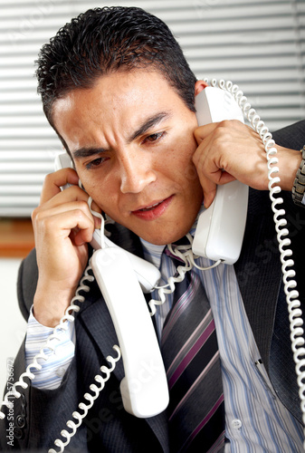 Photo: busy business man with many telephones at once busy business man with many telephones at once
