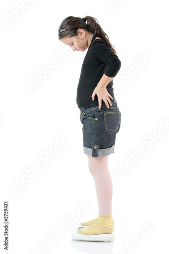 Photo: Little girl standing on a weight scale Little girl standing on a weight scale