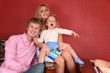 young family laughing in armchair in red room