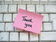 thank you message post-it note on a computer keyboard