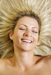 happy woman lying in the sand, sun shining on her face