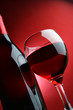 Still-life with bottle and glass of wine over red background