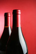 Two corked wine bottles over red background