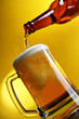 Pouring beer into mug over yellow background