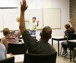 Adult education class raising hands to ask questions.
