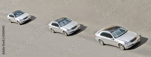 three similar identical twins cars drive in a line