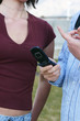 young man and woman standing talking -man holding cell phone