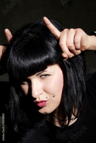 Photo: a woman with black hair and piercing shows horns a woman with black hair and piercing shows horns