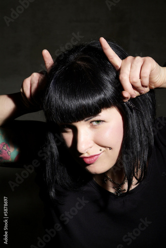 Photo: a woman with black hair and piercing shows horns a woman with black hair and piercing shows horns