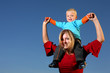 Young boy riding on his mother's shoulders outdoors