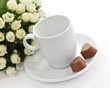 A bunch of flowers, coffee-cup and a pair heart of chocolate.
