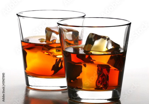 Photo: glass of whiskey with ice cubes on white background glass of whiskey with ice cubes on white background