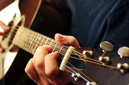 Photo: Hands of a person playing an acoustic guitar close up Hands of a person playing an acoustic guitar close up