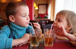 little boy and girl drink juice from glasses through straws little boy and girl drink juice from glasses through straws