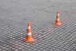 Two red highway cones on paving block Two red highway cones on paving block