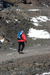 Hiker with poles walking the stony trail on the volcano Etna