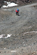 Hiker with poles walking the stony trail on the volcano Etna