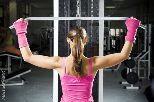 health club: girl in a gym doing weight lifting.