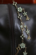 Green gemstone necklace againts brown leather boots