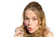 young blond woman putting on makeup with blusher brush