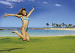 beautiful woman is jumping beside the ocean.