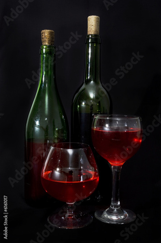 Photo: Red wine bottles and glass isolated over black Red wine bottles and glass isolated over black