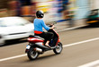Photos : Panning shot of a young girl riding a scooter in a European city