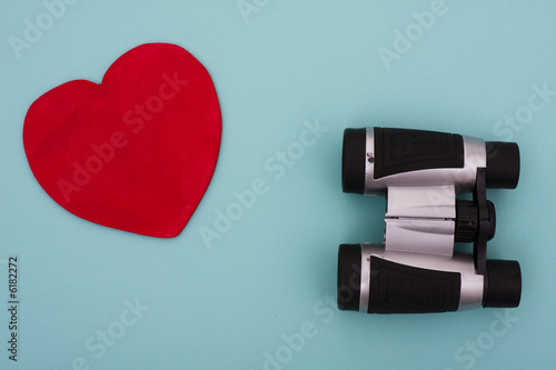 Photo: Heart shape with binoculars on blue background Heart shape with binoculars on blue background