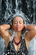 A girl under a relaxing hot spring waterfall at a resort