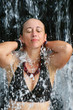 A young woman under a hot spring waterfall in Costa Rica