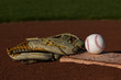 Baseball in a mit sitting on the grass and dirt of a diamond
