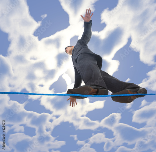 Photo: Young businessman walking on line in the air. Young businessman walking on line in the air.
