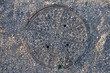 A manhole cover mostly obscured by surrounding gravel A manhole cover mostly obscured by surrounding gravel