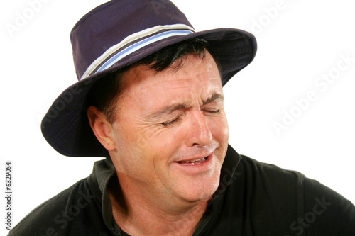 Photo: Middle aged man in a hat bursts into tears. Middle aged man in a hat bursts into tears.