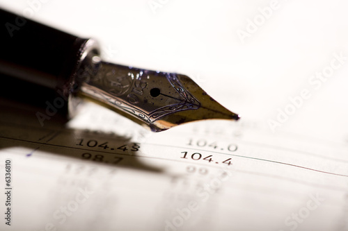 Foto: an expensive pen on a financial magazine an expensive pen on a financial magazine