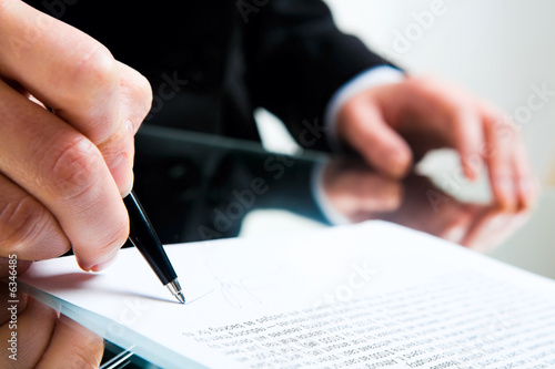 Photo: Closeup of business lady’s hand with pen signing a contract Closeup of business lady’s hand with pen signing a contract