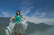 Woman extending a tablecloth for a picnic at the edge of a lake