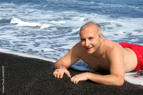 Photo: Mature man on a black sand beach on Big Island, Hawaii Mature man on a black sand beach on Big Island, Hawaii