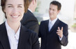Photo: business woman with two businessmen talking in background business woman with two businessmen talking in background