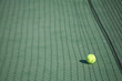 Yellow tennis ball on a green tennis court right next to the net Yellow tennis ball on a green tennis court right next to the net