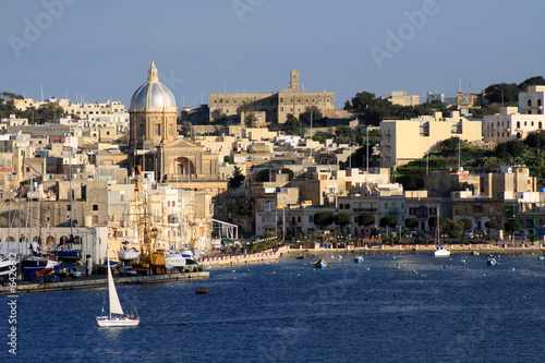 vista della costa maltese con barca a vela bianca
