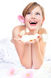 Young woman holding rose petals, laughing, looking up